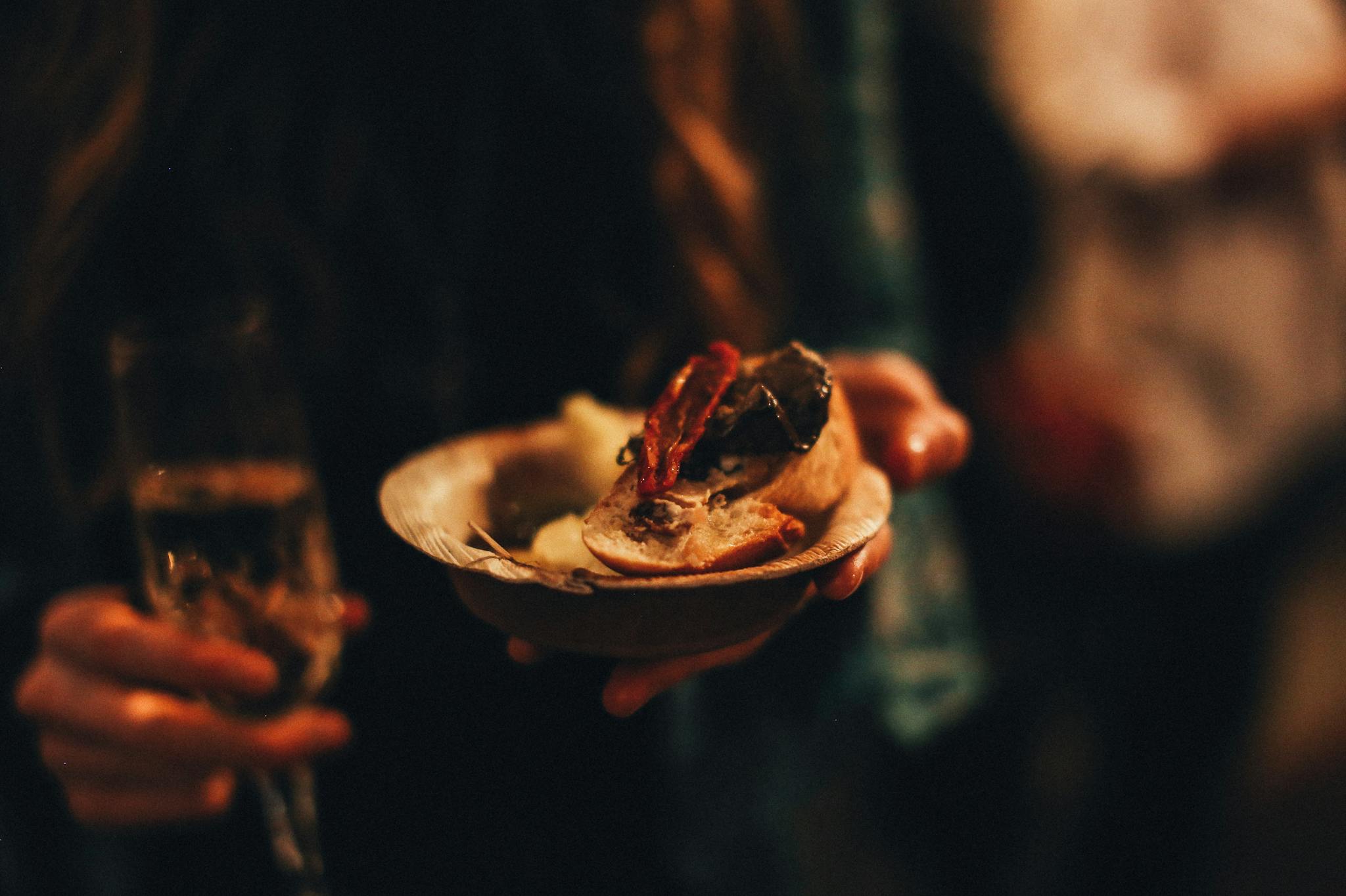 Close-up of a woman holding a plate of gourmet food and a glass of champagne.