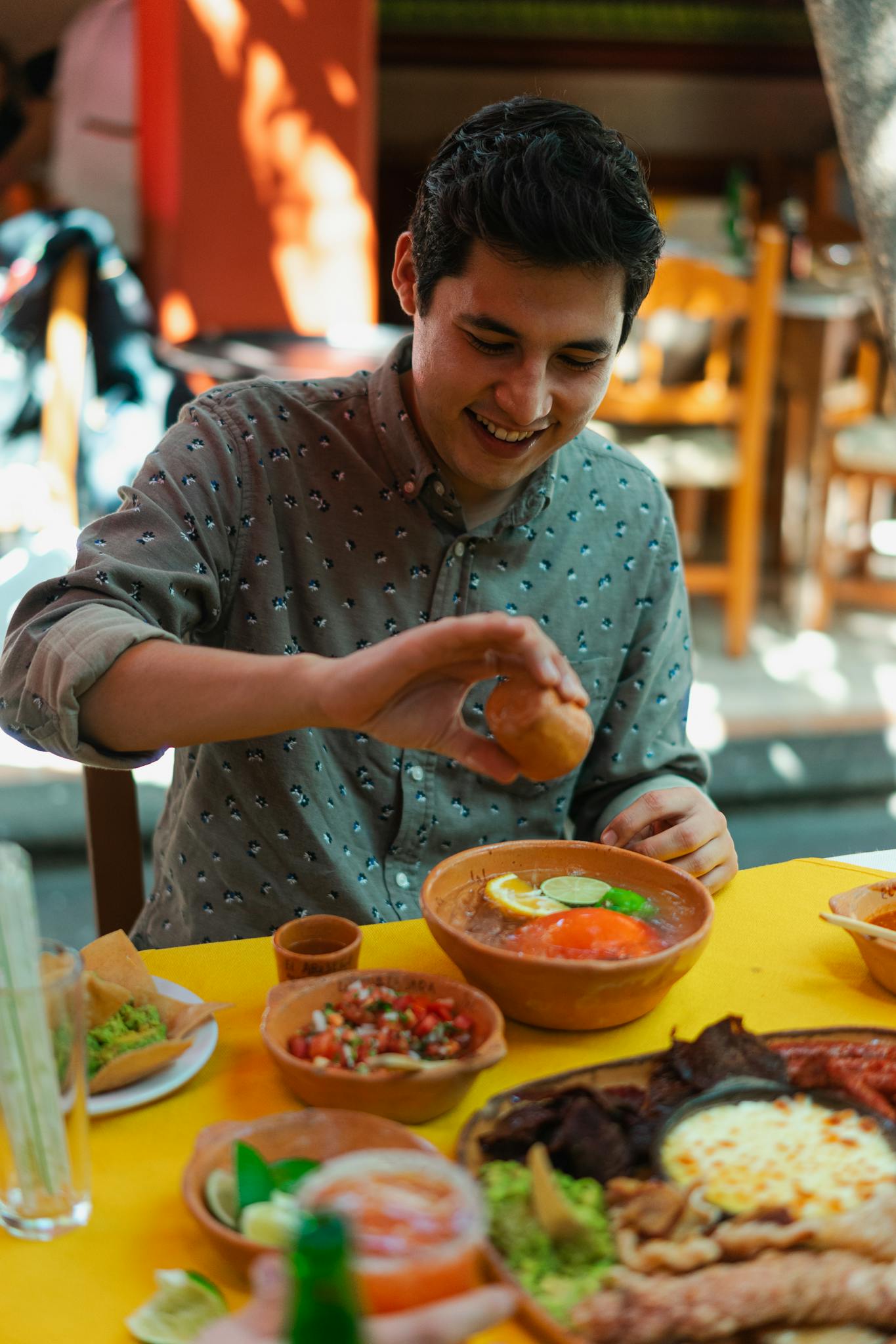 A smiling young man enjoys a colorful Mexican meal at a vibrant restaurant.